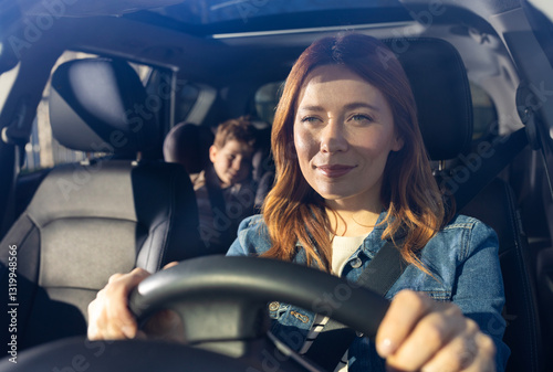 Woman driving car with child in backseat on a sunny day