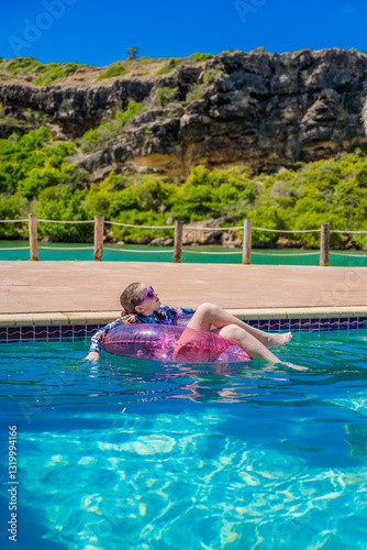 young girl in long sleeve swimsuit floating in a tropical swimming pool