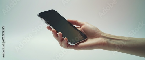 Obraz na płótnie Hand displaying a smartphone with an empty screen against a white background. Concepts for business finance, technology, product marketing, and advertising. w salonie
