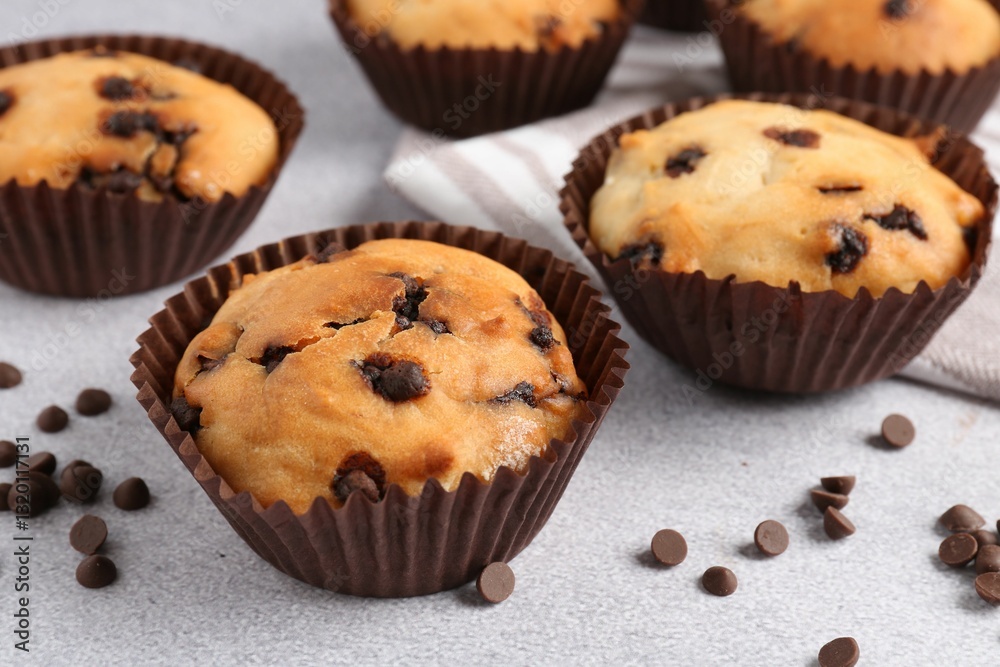 Delicious muffin with chocolate chips on light grey table, closeup
