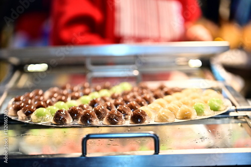 Obraz na płótnie The night market’s golden lights shimmer against the smooth surface of liangyuan desserts. The peaceful yet lively atmosphere of the street food scene captures the charm of local Taiwanese culture. w salonie