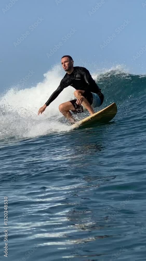 Vertical video of a young man surfing in the clear waters of the Indian Ocean on a sunny day.Bali island.Indonesia Vertical video of a young man surfing in the clear waters of the Indian Ocean on a sunny day.Bali island.Indonesia