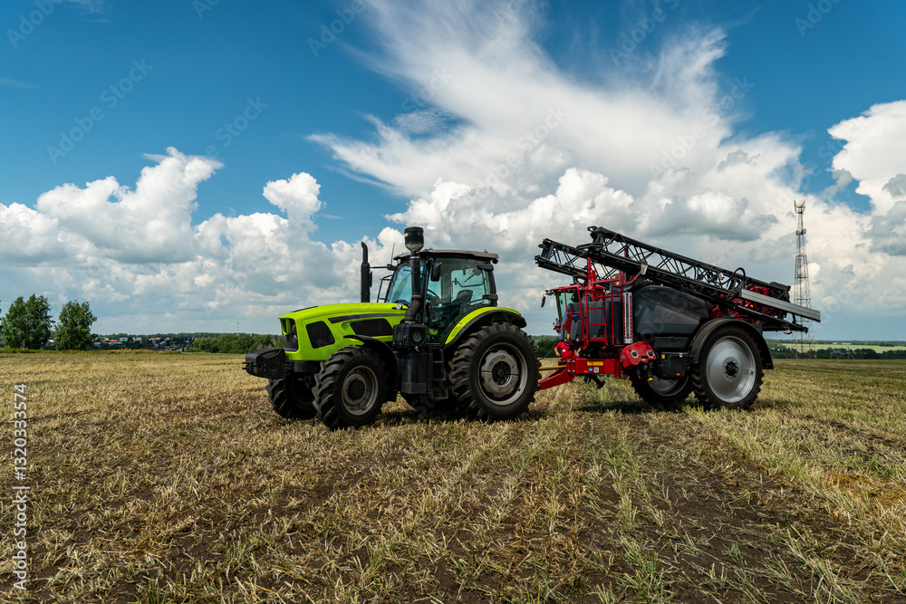 A tractor with a machine for processing plants walks through a green field with grass and a blue sky. automatic treatment of agricultural crops using tractor in the field during the day A tractor with a machine for processing plants walks through a green field with grass and a blue sky. automatic treatment of agricultural crops using tractor in the field during the day
