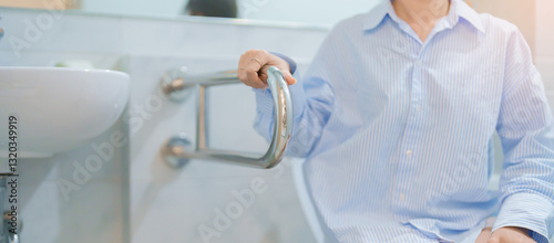 Asian elderly woman use toilet support for older in bathroom, female senior hand holding handrail grab bar. Safety and security in nursing hospital or home. Healthcare concept