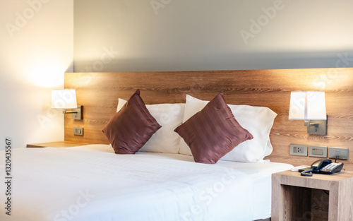 Obraz na plátne A comfortable hotel bedroom with a made-up bed, pillows, lamps, and a telephone