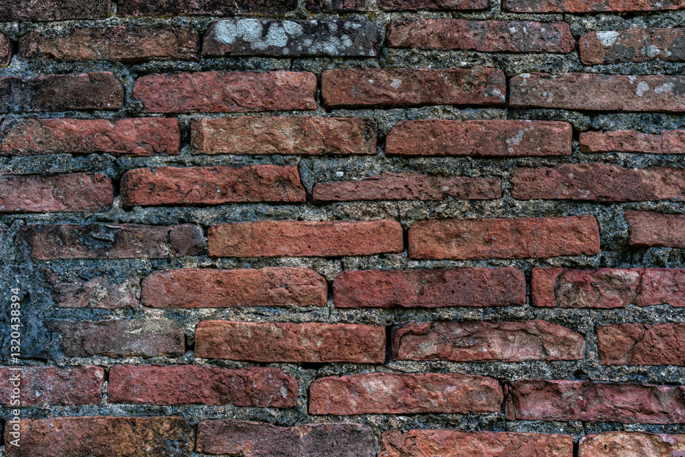 Obraz premium A textured close-up of an aged brick wall, showcasing weathered surfaces and varying tones, ideal for backgrounds or architectural detail.