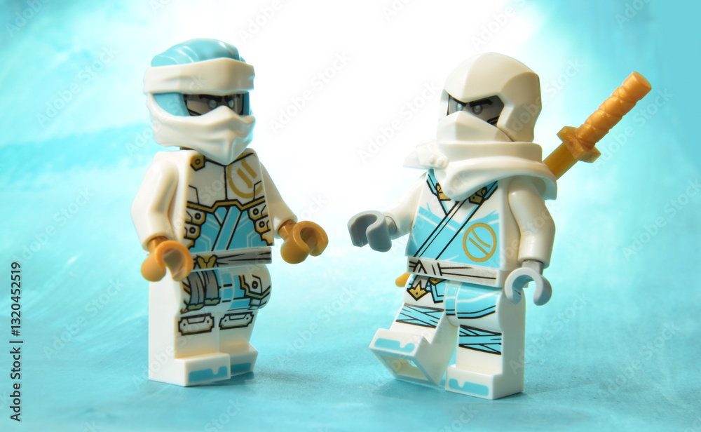Naklejka premium Editorial illustrative image of lego ninjago minifugure of Zane white ice ninja with golden sword weapon on blurred art background