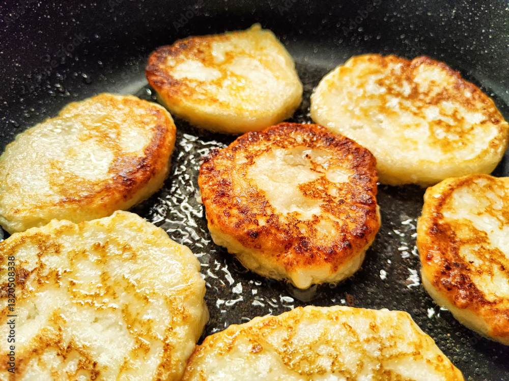 Delicious round potato pancakes frying in a skillet with a golden brown crust Delicious round potato pancakes frying in a skillet with a golden brown crust