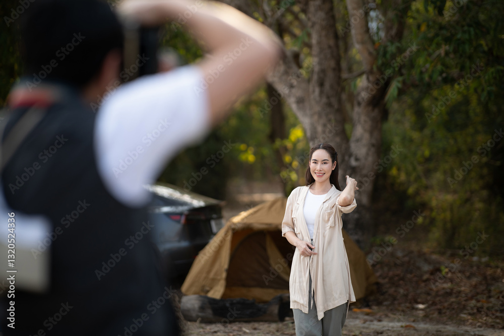 The man is taking a photo of a woman, The woman is posing to the man's camera. Forest camping. The man is taking a photo of a woman, The woman is posing to the man's camera. Forest camping.
