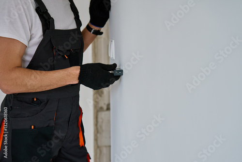 Obraz na płótnie Construction worker in gloves uses laser distance measurer to inspect wall. Builder using digital tool for precision measurement during repair work. Construction and renovation concept w salonie