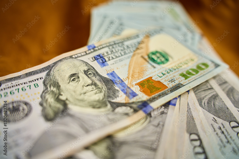 Close-up of US hundred dollar bills stacked on brown fabric surface. Concept of cash transactions, finance, banking and business