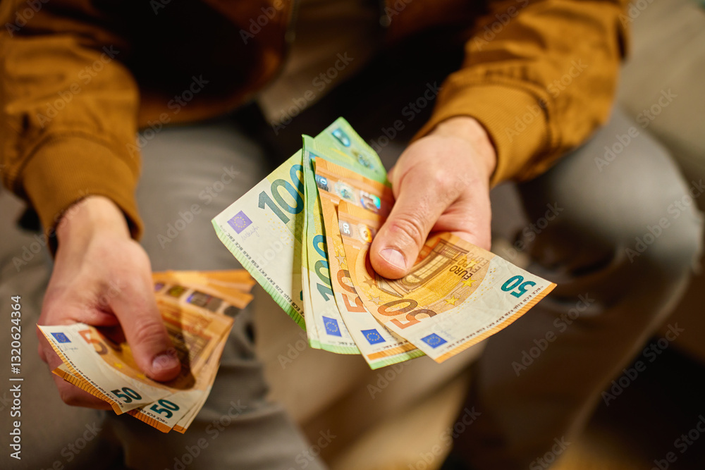 Person counting euro banknotes at home. Person planning his personal finances, sitting on sofa with cash money. Concept of planning home budget, savings and personal finances