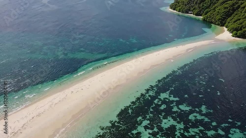 Beautiful aerial view of a sandbar extending into the turquoise ocean, surrounded by clear waters and lush green coastline.