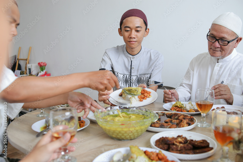 Young Muslim Teenage Boy Having Special Food Served By Family Hand During Eid Celebration Young Muslim Teenage Boy Having Special Food Served By Family Hand During Eid Celebration