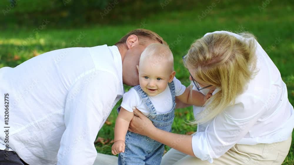 Loving mom and dad tenderly kissing adorable baby on cheek during picnic in park. Parental moment of joyful affection for child, showing love and care for toddler. Summer family weekend together Loving mom and dad tenderly kissing adorable baby on cheek during picnic in park. Parental moment of joyful affection for child, showing love and care for toddler. Summer family weekend together