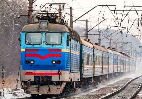 Passenger train rapidly moving along snow covered tracks in Kyiv Oblast of Ukraine