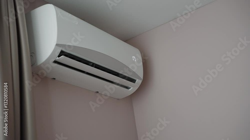 Woman holding air conditioner remote control and setting cooling temperature on split system to 17 degrees, in hotel room, at home. Concept of air cooling in hot room, climate control at home