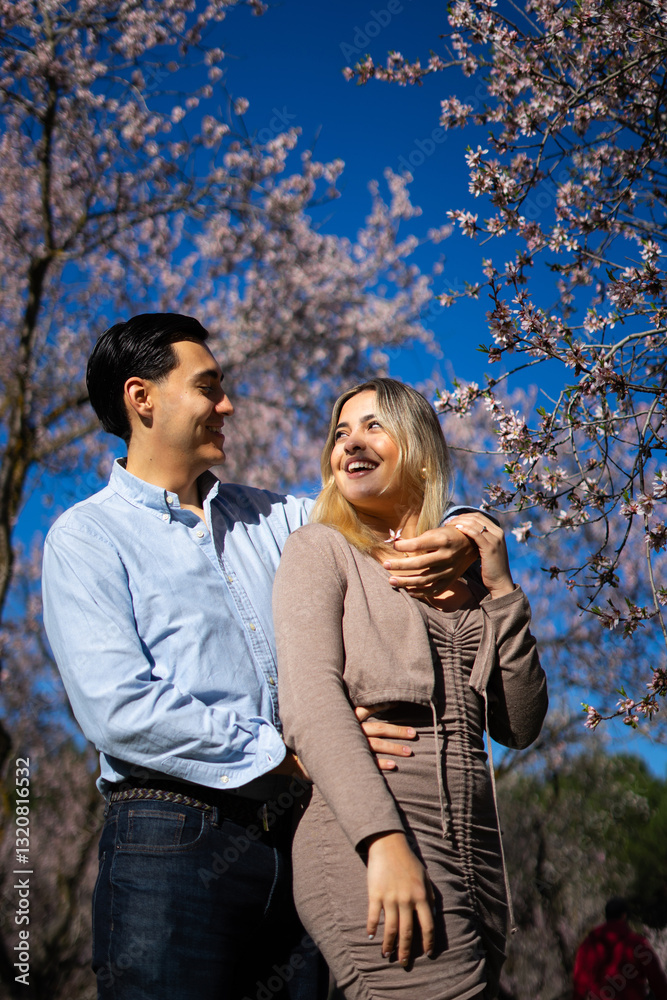 Young latin couple embracing under blooming almond trees in springtime Young latin couple embracing under blooming almond trees in springtime