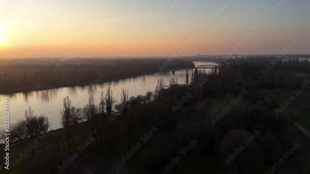 Po River flowing under a bridge in Cremona against the colorful sunset sky in winter time. Po River flowing under a bridge in Cremona against the colorful sunset sky in winter time.