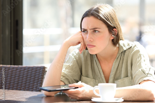Cuadro en lienzo Angry woman in a bar holding phone and thinking