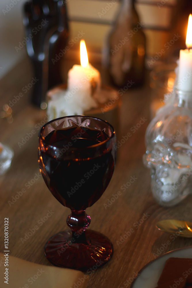Books, lit candles, red wine, snacks and various deocration on the table. Dark academia or Halloween concept. Selective focus.
