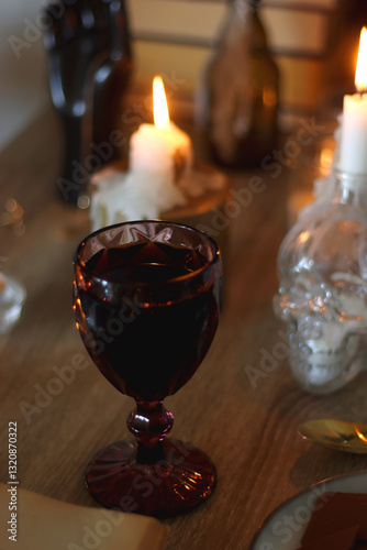 Books, lit candles, red wine, snacks and various deocration on the table. Dark academia or Halloween concept. Selective focus.
