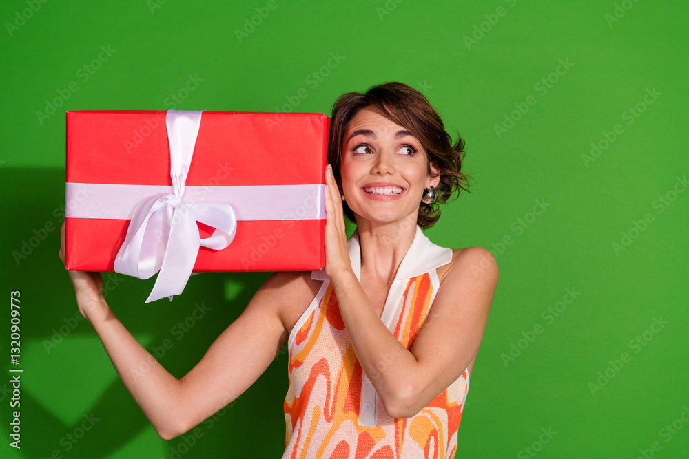 Photo portrait of pretty young girl hold big giftbox look empty space wear trendy colorful outfit isolated on green color background Photo portrait of pretty young girl hold big giftbox look empty space wear trendy colorful outfit isolated on green color background