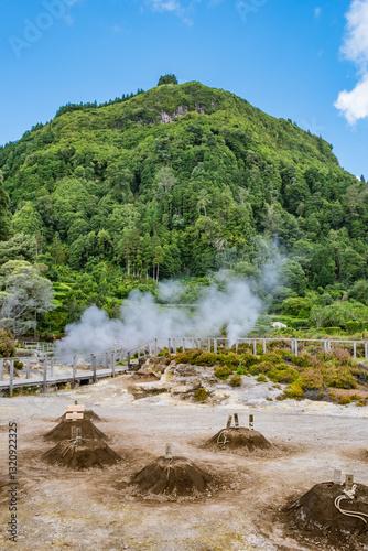 Heaps of soil in the cooking sulfur fumaroles, vapors in the form of smoke and green mountain in the background, Furnas, São Miguel - Azores PORTUGAL