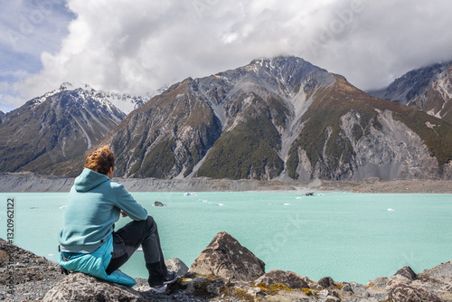 Female tourist enjoying breathtaking view of tasman lake and southern alps in new zealand