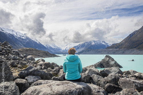 Female tourist enjoying breathtaking view of tasman lake and southern alps in new zealand