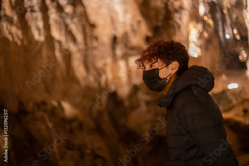 Tourist wearing face mask exploring valporquero caves in spain	