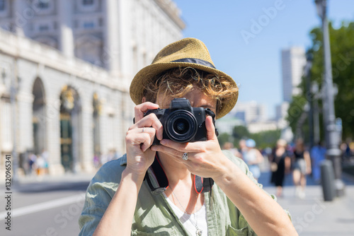 Tourist taking photos in madrid city center with royal palace in background