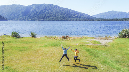 Hikers jumping by lake ianthe, south island, new zealand
