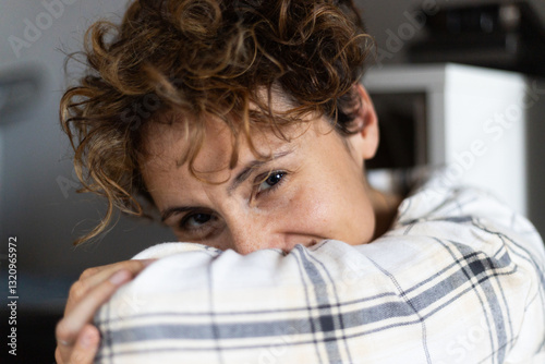 Woman hiding face with sleeve smiling at home