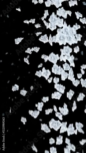 Falling salt crystals against black background in slow motion