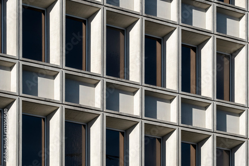 Symmetrical concrete grid of a brutalist-style building with repetitive windows.