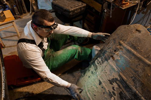 Cuadro en lienzo Auto Mechanic Inspecting Dirty Vehicle Undercarriage in Garage Workshop
