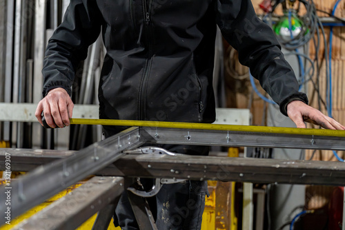 Dans un atelier de métallerie, un homme mesure les barres de métal pour réaliser son projet L'art et la précision des métalliers dans leur environnement de travail.