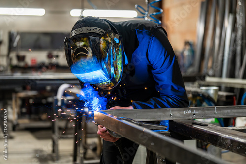 Konstfotografi Dans un atelier de métallerie, un homme qui est en train de couper des barres de métal
