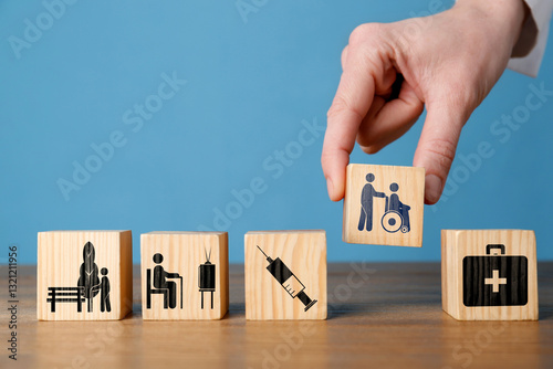 Woman arranging wooden cubes with healthcare icons on table against blue background, closeup. Space for text