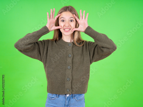 Fotografía beautiful teen girl wearing green sweater keeping eyes opened to find a success opportunity