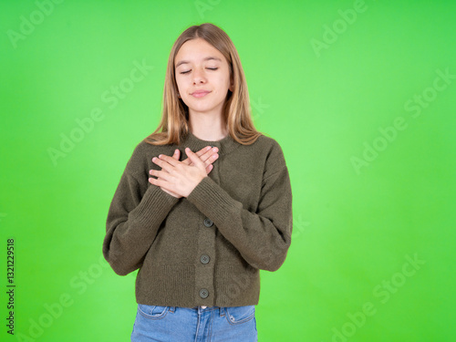 beautiful teen girl wearing green sweater smiling with hands on chest with closed eyes and grateful gesture on face. Health concept.
