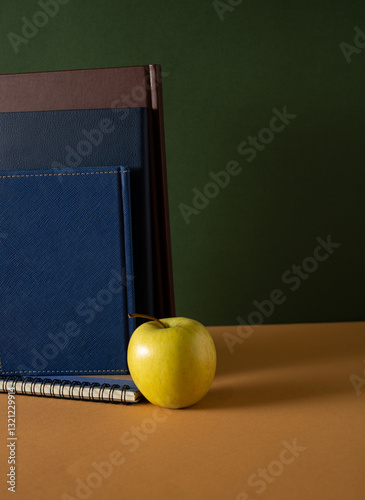 Healthy yellow apple on a teacher's brown desk in front of a green school blackboard