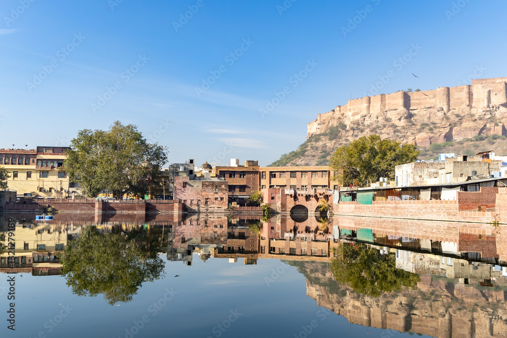 Obraz premium pristine calm lake with reflection of historical mehrangarh fort and houses around at morning