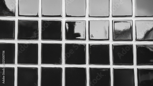 Close-up of a grid of small square tiles. the tiles are arranged in a grid-like pattern, with each tile having a different color - black, white, and gray.