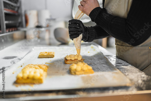 Fotografi Pastry chef decorating pastries with cream using piping bag in bakery
