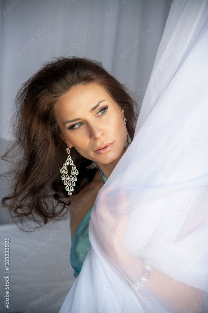 Woman in elegant attire poses gracefully by the bed with sheer fabric Woman in elegant attire poses gracefully by the bed with sheer fabric