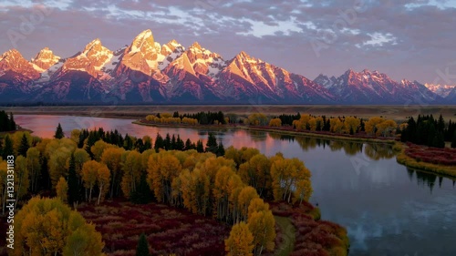 Majestic sunrise paints the Grand Teton mountain range and the Snake River in vibrant hues during the fall season