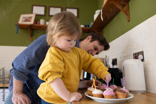 Child Carefully putting birthday candles into cupcakes