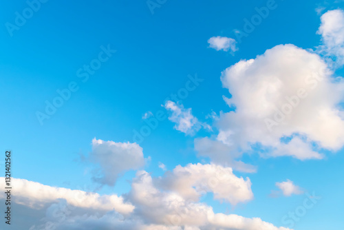 Blue sky background with white clouds and silhouette of flying airplane